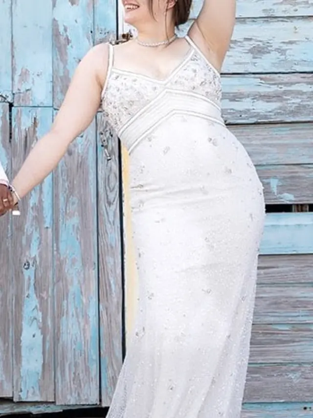 A bride in a beaded slip-style gown beside a weathered blue door